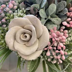 White, ceramic rose in a flower bouquet.

Handcrafted ceramic flower.