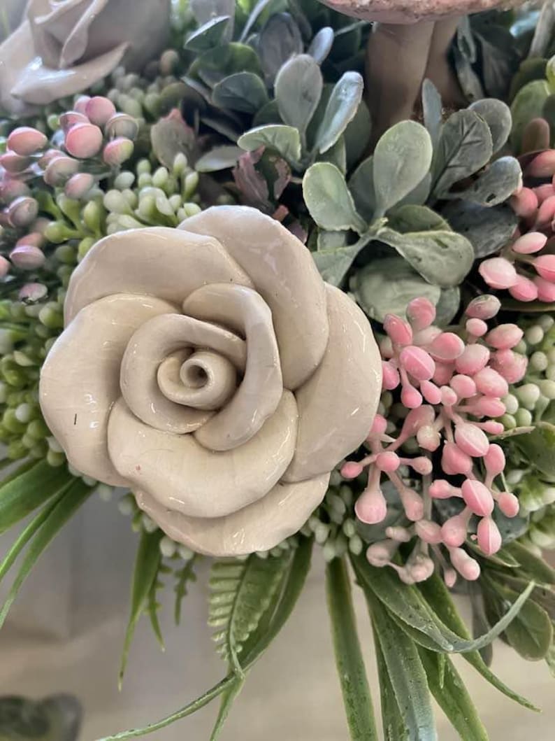 White, ceramic rose in a flower bouquet.

Handcrafted ceramic flower.