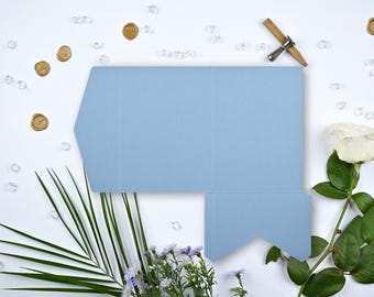 May include: A light blue favor box with a white rose and green leaves on a white background. There are also small gold wax seals and clear glass beads scattered around the box.