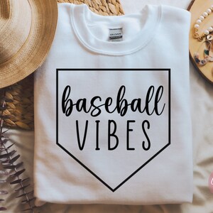 May include: White sweatshirt with a black baseball diamond graphic and the text "baseball vibes" in black script.