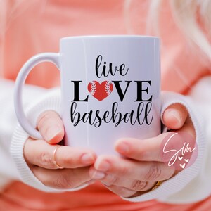 May include: White ceramic mug with a black and red design. The mug says "live love baseball" with a red baseball heart.