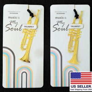 Puede incluir: Dos marcadores de trompeta de color dorado con el texto "music is my soul" y "TRUMPET" sobre un fondo blanco con arcos iris. Los marcadores están empaquetados en tarjetas blancas con el texto "INSTRUMENT STYLE BOOKMARK" y "US SELLER Fast Shipping From USA".