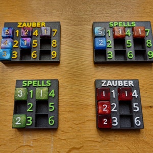 Könnte beinhalten: Vier schwarze Tabletts mit Gitterfächern, die jeweils Würfel mit verschiedenen Farben und Zahlen enthalten. Die Tabletts sind mit "ZAUBER" und "SPELLS" beschriftet.