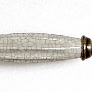 May include: White ceramic cabinet pull with a crackled finish and brass end caps.