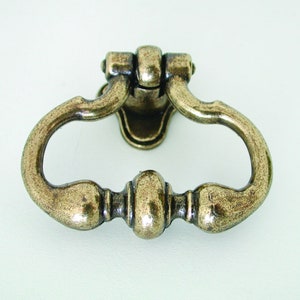 May include: Antique brass cabinet pull with a ring handle and a decorative knob. The handle is shaped like a teardrop and has a smooth, polished finish.