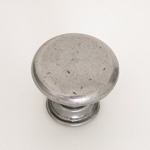 May include: A silver metal cabinet knob with a round top and a textured finish.