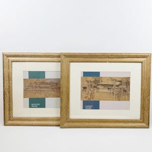 Pode incluir: Dois esboços arquitetónicos emoldurados. As molduras douradas têm um acabamento texturizado. A obra apresenta um esboço de uma casa com um bloco de cor verde-azulado, azul e bege. O texto "BOYNTON HOUSE" e "CHENEY HOUSE" é visível.