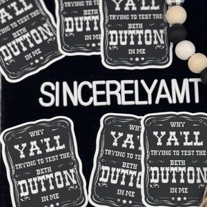 May include: Five black and white stickers with the text "Why Ya'll Trying to Test the Beth Dutton in Me" on each. The stickers are rectangular with rounded corners and a white border.