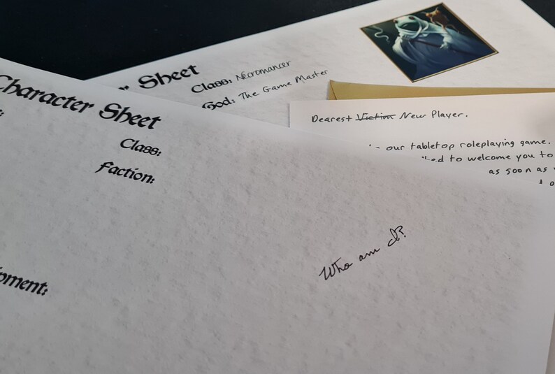 May include: A white sheet of paper with the words "Character Sheet" and "Class: Necromancer" written on it. The sheet is folded in half and there is a gold envelope on top of it. The envelope has the words "Dearest Victim New Player" written on it.