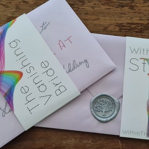 Op de afbeelding: Twee roze enveloppen met een waszegel met een boomontwerp. Eén envelop heeft een witte kaart met een regenboogontwerp en de tekst "The Vanishing Bride" en de andere envelop heeft een witte kaart met een regenboogontwerp en de tekst "Within The Story" en het websiteadres "WithinTheStory.co.uk".
