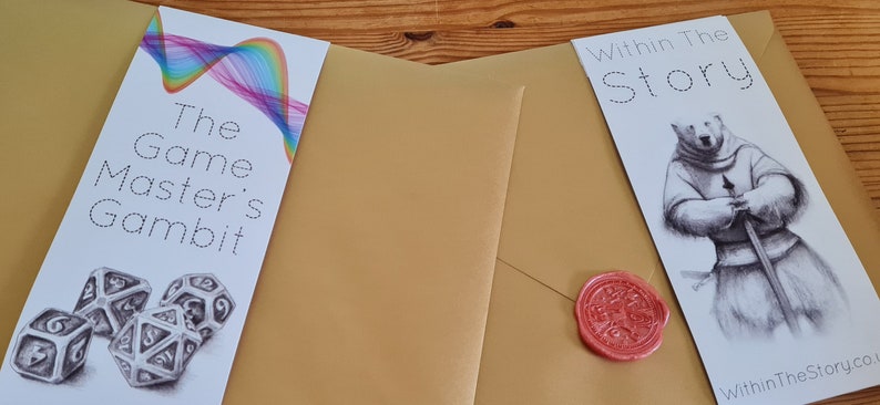 May include: Two bookmarks, one with a rainbow design and the text "The Game Master's Gambit" and dice, the other with a polar bear in armor and the text "Within The Story".