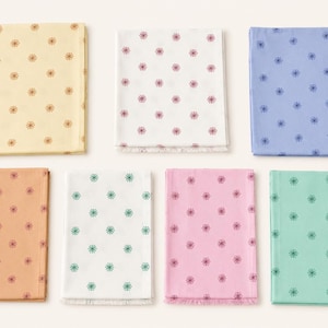 May include: Seven rectangular fabric swatches arranged in two rows. The colors include pale yellow, white, light blue, peach, white, pink, and mint green. Each piece features a repeating pattern of small, dark, star-like floral motifs.