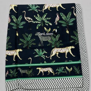May include: A dark blue fabric with a repeating pattern of zebras, leopards, birds, and palm trees. The fabric has a green stripe and a black and white striped border. The text "TanLoom" is visible.
