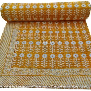 May include: A mustard yellow and white floral patterned quilt. The quilt features a repeating pattern of white flowers and stems on a yellow background. The border has a striped design and floral accents.