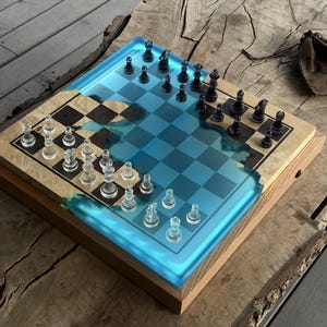 May include: A distinctive chess set with a wooden board incorporating a blue resin river design. The board features a traditional chequered pattern and is populated with clear and black chess pieces. The set is presented on a wooden surface.