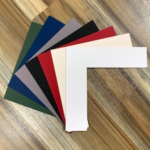 May include: A set of 10 different coloured mat boards, each with a white L-shaped mat cut out. The mat boards are arranged in a fan shape, with the white mat in the centre.