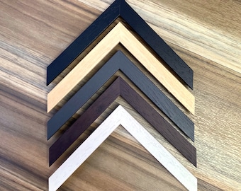 May include: Five picture frames in different colors, arranged in a pyramid shape. The frames are white, brown, gray, beige, and black.