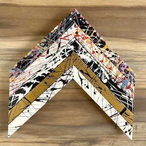 May include: A multi-layered picture frame with a white, gold, black and multi-coloured splatter paint design.