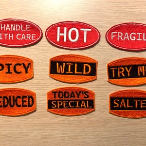 May include: Nine oval-shaped iron-on patches with various phrases, including "Handle With Care", "Hot", "Fragile", "Spicy", "Wild", "Try Me", "Reduced", "Today's Special", and "Salted". The patches are orange and red with black lettering.
