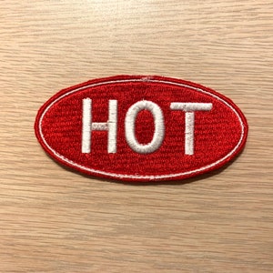May include: Red oval patch with white embroidered text that reads "HOT".