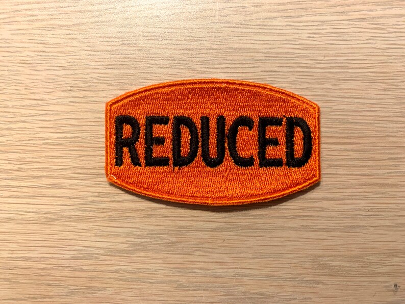 May include: Orange fabric patch with the word "REDUCED" embroidered in black thread.