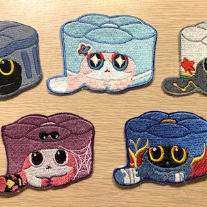 Può includere: Sei toppe ricamate da stirare che rappresentano diversi rotoli di sushi colorati con facce di gatto. Ogni toppa ha un colore e un design diverso, tra cui blu, bianco, viola e rosa.