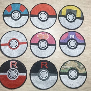 May include: Ten round embroidered iron-on patches featuring different designs. The patches are white, red, black, blue, yellow, and grey. Some patches have letters, hearts, and other symbols.