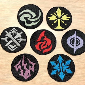 May include: Seven embroidered patches with various designs on a wood background. The patches are black with different colored designs. The designs include a swirl, a tree, a sword, a hand, a musical note, a snowflake, and a symbol.