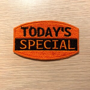 May include: Orange embroidered patch with black text that reads "TODAY'S SPECIAL".