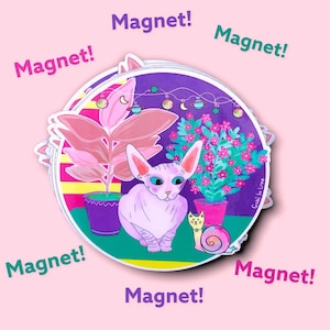 Puede incluir: Un imán redondo con una ilustración de un gato Sphynx, plantas en macetas y un caracol, con el texto "Magnet!". El diseño es colorido, con un fondo rosa y un estilo caprichoso.