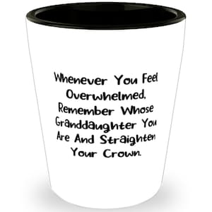 May include: White ceramic shot glass with a black rim. The glass has a quote printed on it that reads: "Whenever You Feel Overwhelmed, Remember Whose Granddaughter You Are And Straighten Your Crown."