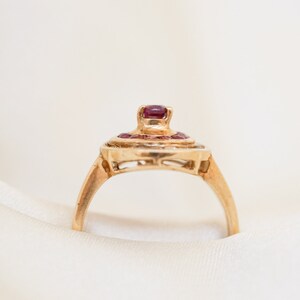 May include: A gold ring with a cluster of red gemstones set in a delicate, intricate design.