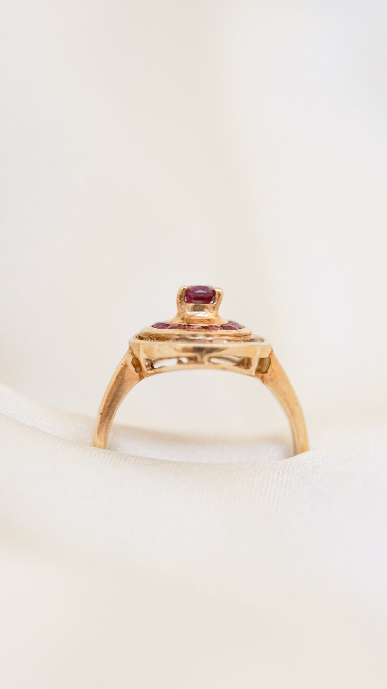 May include: A gold ring with a cluster of red gemstones set in a delicate, intricate design.