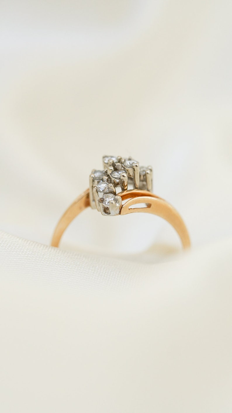 Pode incluir: Um anel de ouro com um grupo de pequenos diamantes engastados em um design delicado.