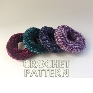 May include: Four plush, crocheted hair scrunchies in shades of burgundy, teal, navy, and lavender. The text "CROCHET PATTERN" is displayed in a light green font below the scrunchies.