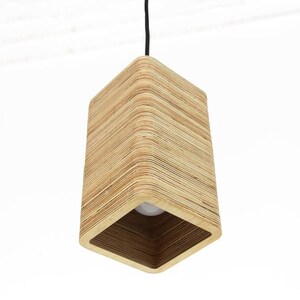 May include: A modern, rectangular pendant light fixture. The light's shade is constructed from layered, light-colored wood, creating a textured effect. The fixture hangs from a black cord, and the light bulb is visible.