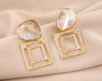 May include: A pair of gold earrings with a square frame and a large, irregular, iridescent pearl-like stone.