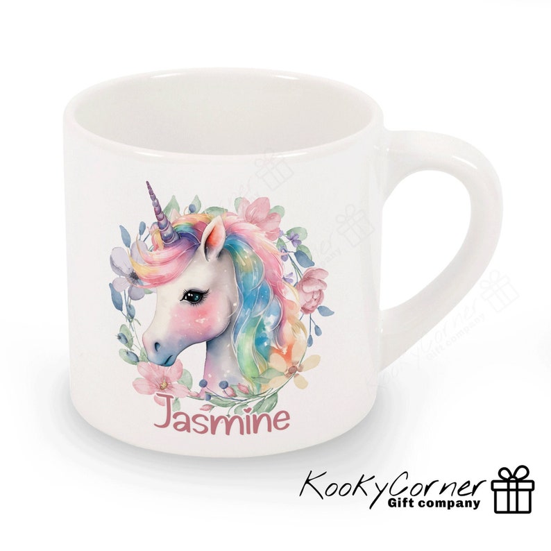 May include: White ceramic mug featuring a colourful unicorn illustration and the name "Jasmine" printed on the front. The unicorn has a rainbow mane and tail and is surrounded by pink and purple flowers.