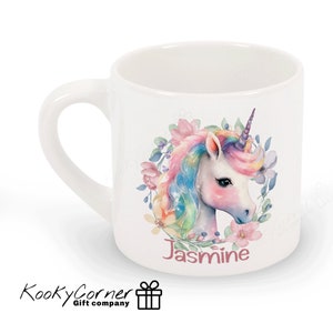 May include: White ceramic mug featuring a colourful unicorn illustration and floral wreath. The unicorn has a pink, blue and yellow mane and tail. The mug is personalised with the name "Jasmine".