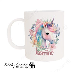 May include: White ceramic mug featuring a colourful unicorn illustration surrounded by flowers. The unicorn has a rainbow mane and tail. The mug is personalised with the name "Jasmine" printed on it.