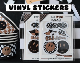 May include: A set of vinyl stickers featuring a skateboard, a star, and a smiley face with lightning bolts. The stickers are in black, white, and brown with a checkered pattern. The text on the stickers reads "Pete's 5th Birthday!" and "HAR" and "ELIJAN".
