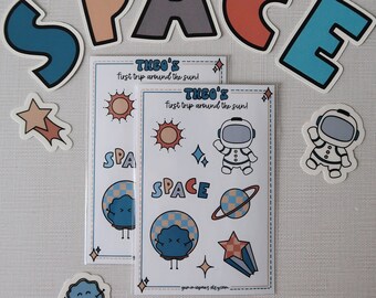 May include: Two sheets of stickers with a space theme. The stickers feature a blue astronaut, a yellow sun, a blue planet with a face, a blue and white checkered planet, a red and white star, a blue and white planet with rings, and the words "THEO'S First trip around the sun!" and "SPACE".