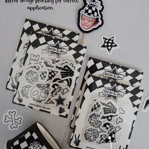 Puede incluir: Un conjunto de pegatinas en blanco y negro con una calavera, huesos, corazones, estrellas y el texto "Bad to the Bone". Las pegatinas est&aacute;n empaquetadas en bolsas de pl&aacute;stico transparentes con un fondo a cuadros.