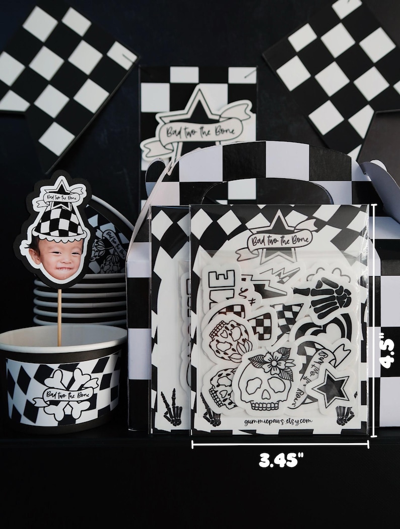 Puede incluir: Un conjunto de art&iacute;culos para fiestas en blanco y negro con un tema de calavera y huesos cruzados. El conjunto incluye un adorno para cupcake, una hoja de pegatinas y una taza. La hoja de pegatinas presenta una variedad de dise&ntilde;os de calaveras y huesos cruzados, incluyendo una calavera con una flor, una calavera con una corona y una calavera con un pa&ntilde;uelo. El texto en la hoja de pegatinas dice "Bad to the Bone" y "gummiepaws elsy.com". La hoja de pegatinas mide 11,4 cm de alto y 8,8 cm de ancho.