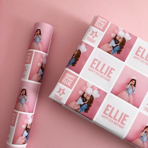May include: Custom birthday wrapping paper featuring a repeating grid pattern of pink and white squares. The design includes photographs of a child, the text "ELLIE HAPPY 6TH BIRTHDAY," and a star graphic with the text "6 TODAY" in pink and white.