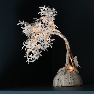Scultura luminosa con un gatto, in partitura musicale tagliata a mano