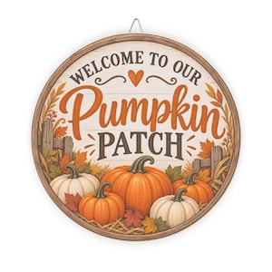 Op de afbeelding: Een rond houten bord met de tekst WELCOME TO OUR PUMPKIN PATCH en een harticoon. Het ontwerp bevat oranje en witte pompoenen, herfstbladeren en een houten hek op een lichte achtergrond met een bruine, cirkelvormige omlijsting.
