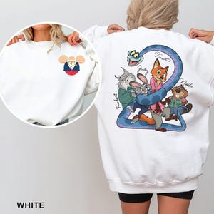 Op de afbeelding: Witte sweatshirt met een cartoonafbeelding van personages uit een film. De voorkant heeft een op Mickey Mouse ge&iuml;nspireerd ontwerp. De achterkant toont een blauwe slang en verschillende dierenfiguren. Het woord "WHITE" staat onderaan.
