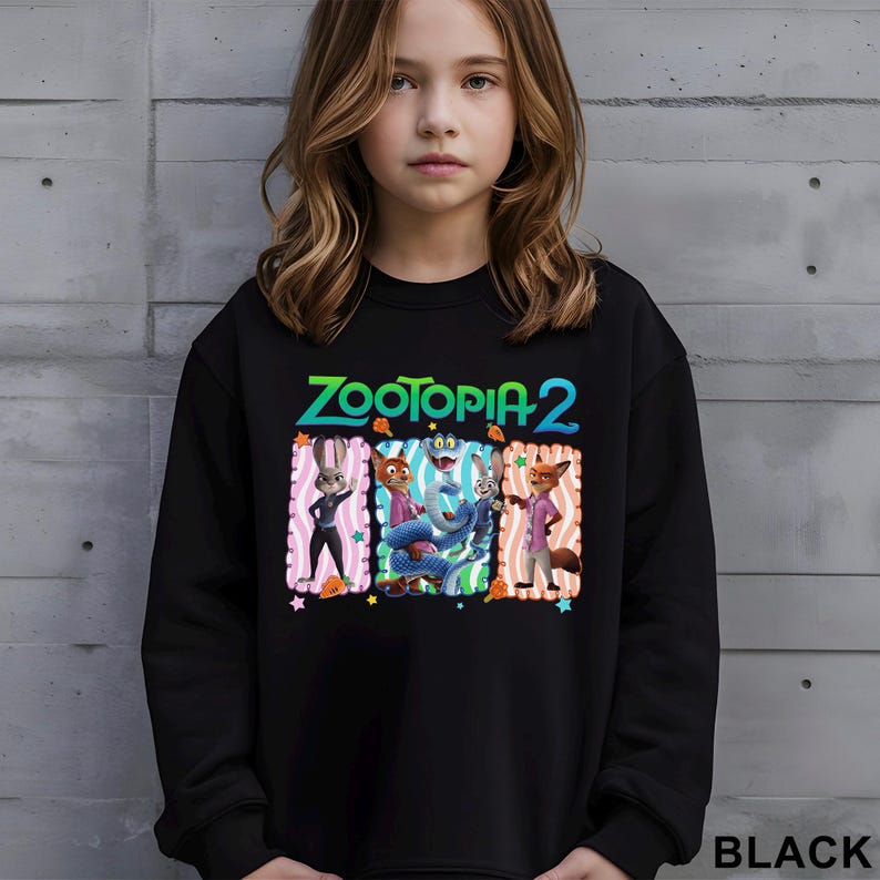 Puede incluir: Sudadera negra con el texto "ZOOTOPIA 2" en verde y azul. El gr&aacute;fico incluye personajes de dibujos animados en marcos rectangulares coloridos. La palabra "BLACK" est&aacute; impresa en blanco en la parte inferior derecha.