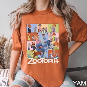 May include: Burnt orange t-shirt featuring a colorful graphic from the animated movie "Zootopia." The design includes various characters in a grid layout, with the movie title in white block letters. The shirt has short sleeves.
